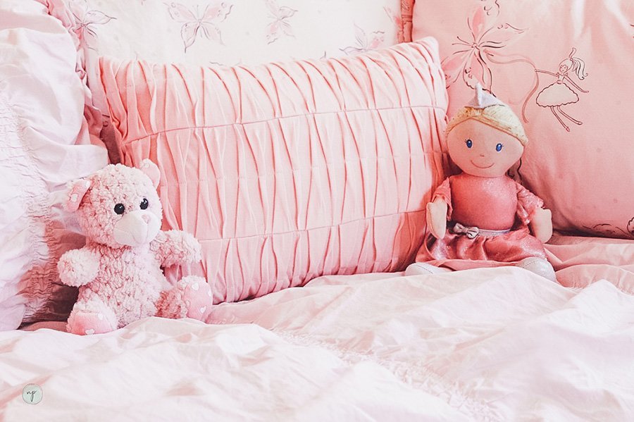 close up of princess doll and stuffed bear on bed