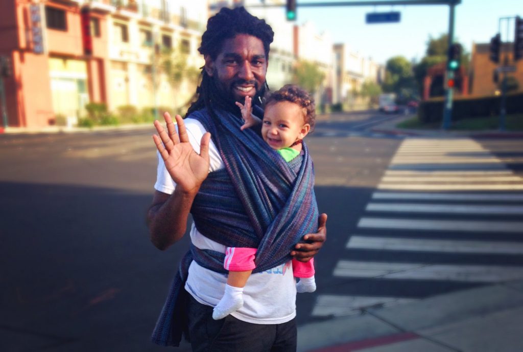 babywearing dad waves at camera