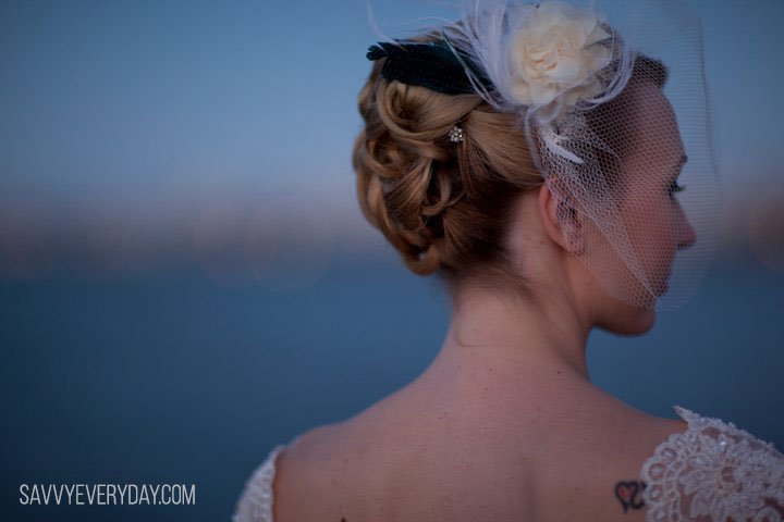 Picture of Shari in wedding dress with back to camera and head turned toward camera slightly. Tattoo on right shoulder blade.