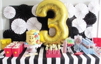 Image of a LEGO-themed 3rd Bday table with balloon, cake and snacks