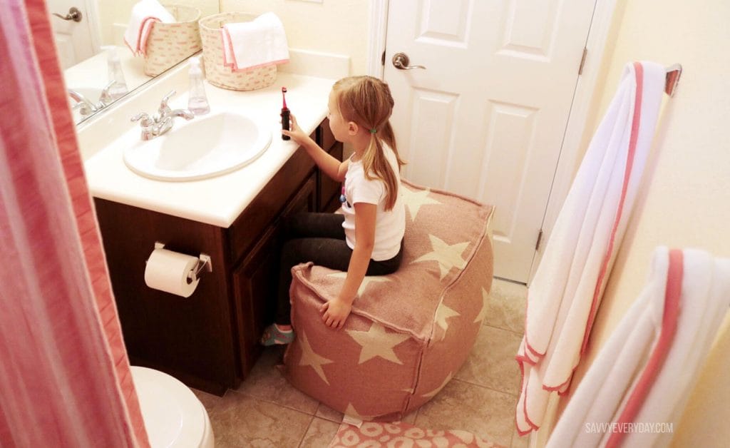 S sitting on pouf in coral bathroom