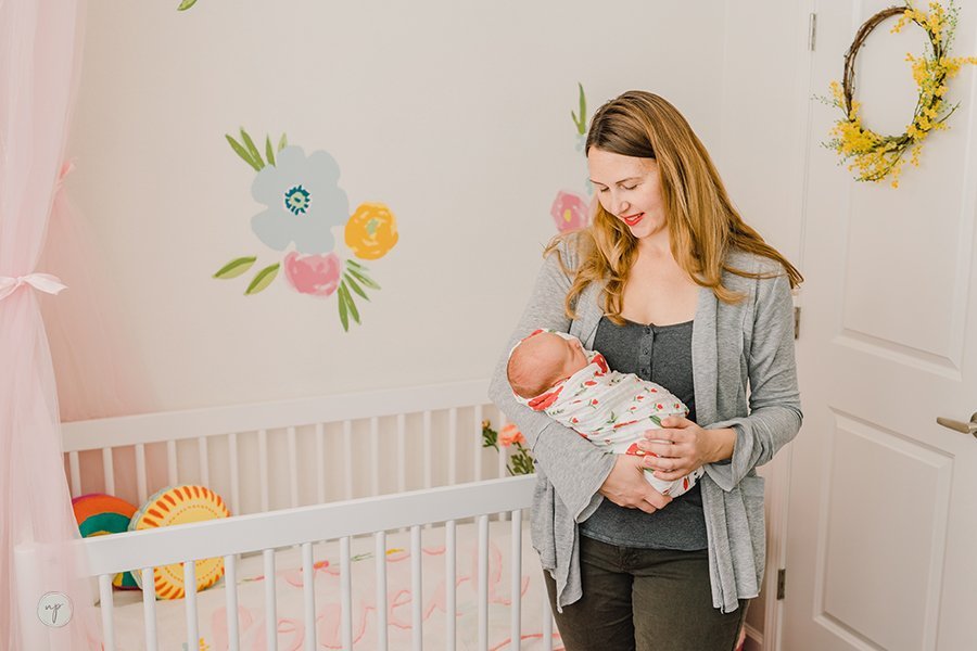 holding Nora in floral bohemian nursery