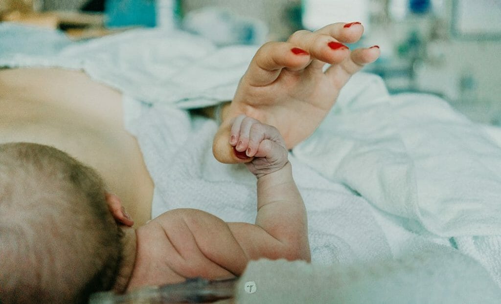 breastfeeding myths- baby with hand gripping mom's thumb