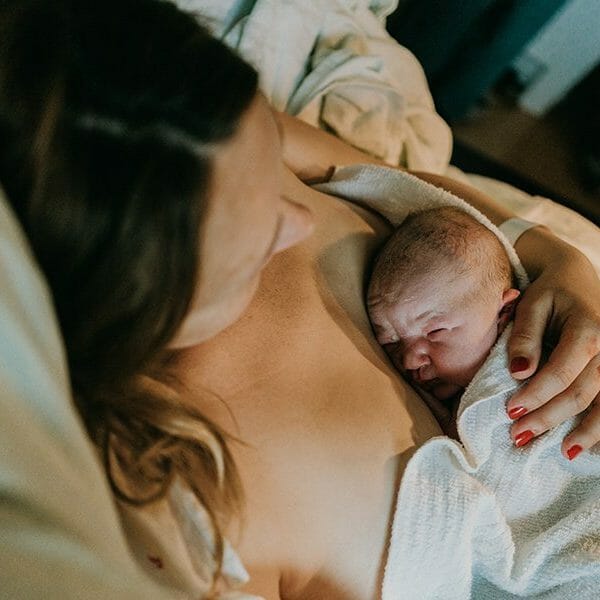 baby laying on mother's chest during golden hour