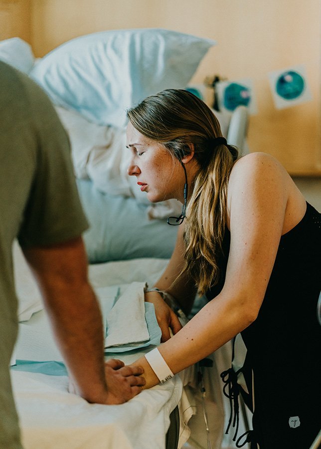 birthing mother works through contraction at side of hospital bed