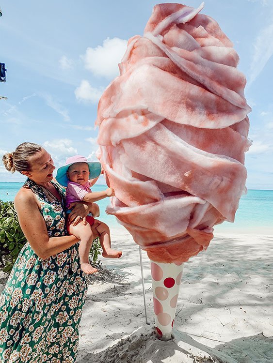 mom holding baby in front of a giant cotton candy