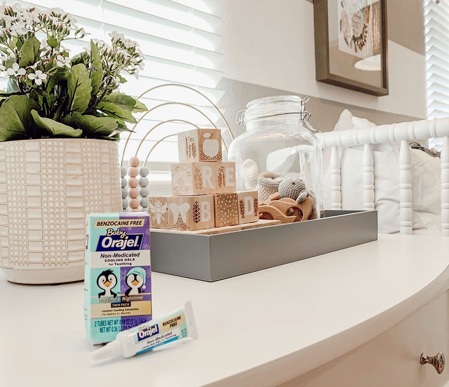 Orajel teething gels sitting on nursery room dresser