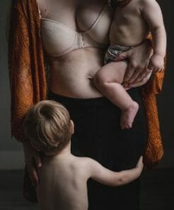 postpartum mom body with babies postpartum mom with baby on hip and toddler hugging her legs