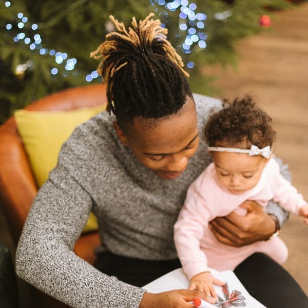 dad colors with baby daughter near Christmas tree