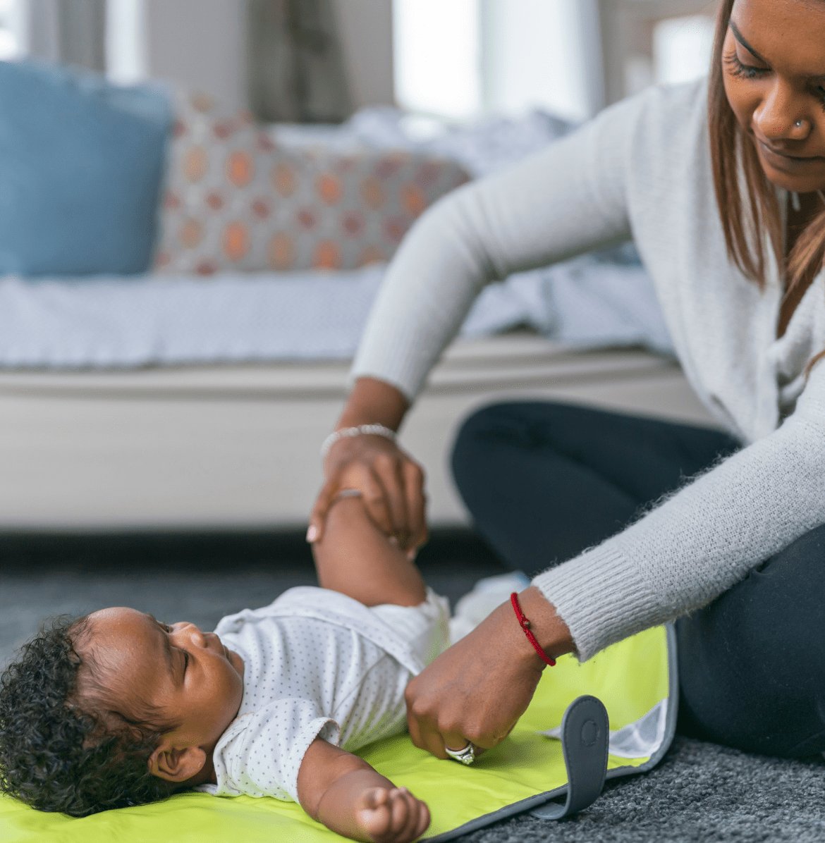 mom changing baby diaper on floor