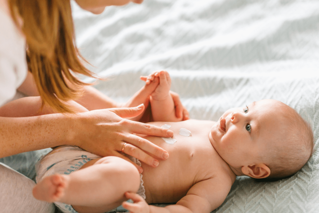 mom applies lotion to her baby before baby massage